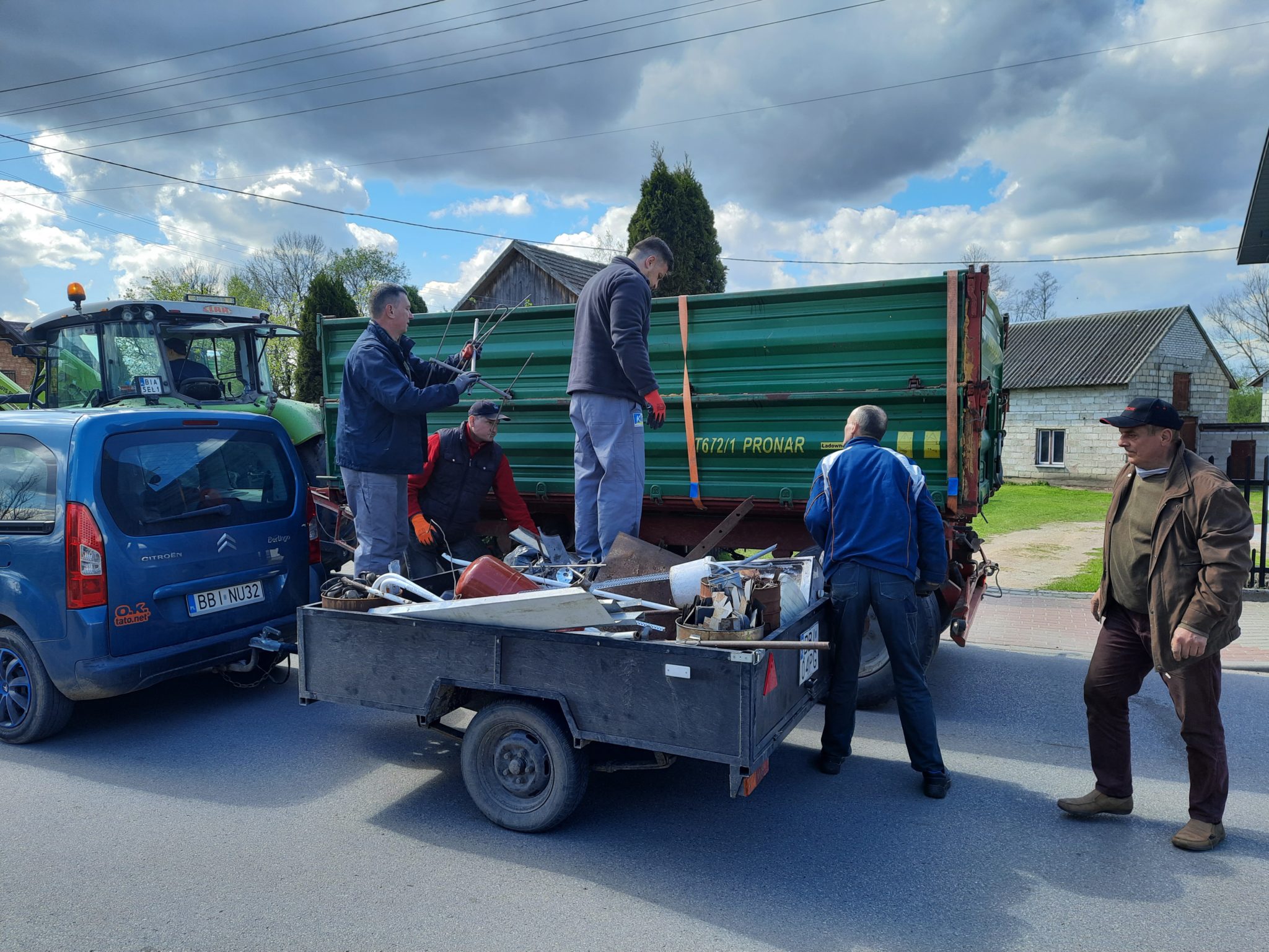 Mężczyźni ładują zebrany złom na przyczepę obok ciężarówki podczas zbiórki w Brańsku.