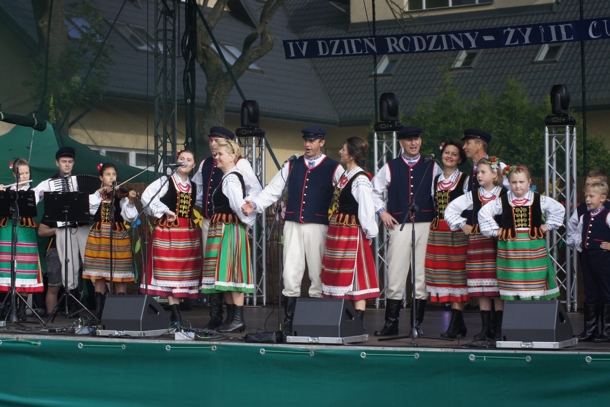 Grupa osób w strojach ludowych prezentuje się na scenie podczas wydarzenia "IV Dzień Rodziny".