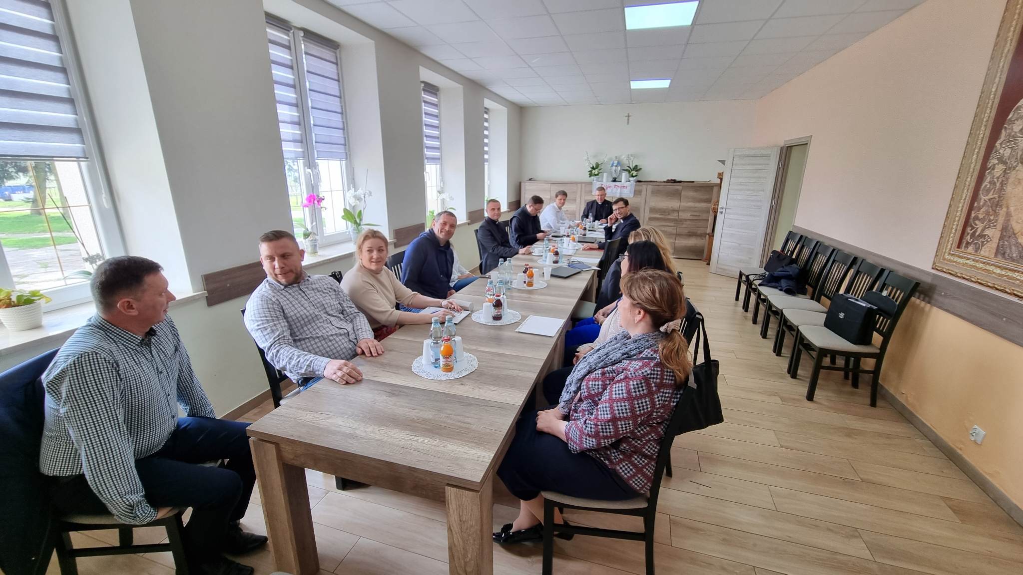 Uczestnicy wizytacji w Hodyszewie siedzący przy długim stole w sali spotkań.